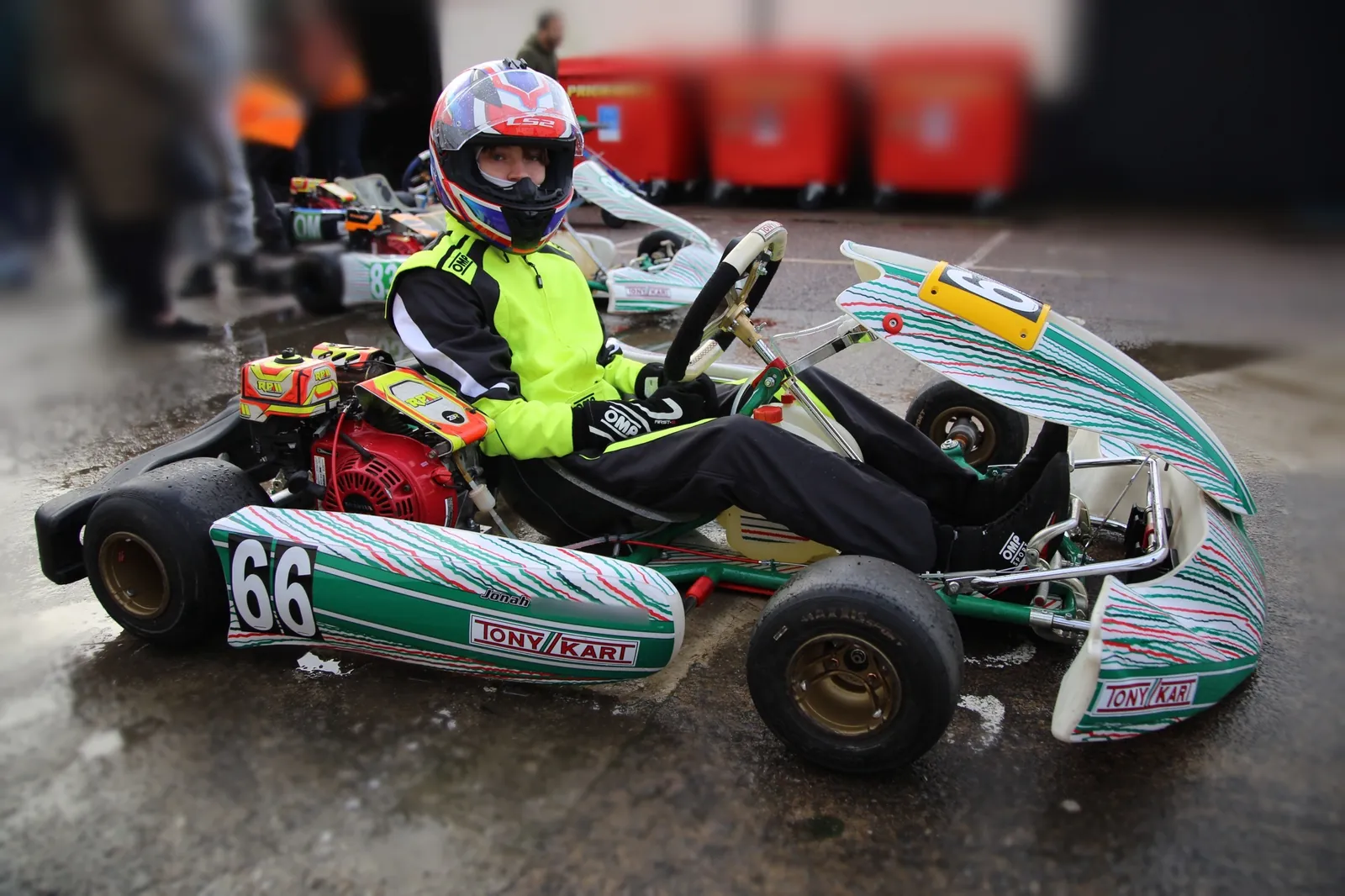 Green and white Tony Kart Racer with a red restricted Honda GX200 engine and a yellow number plate, with a junior driver seated in it