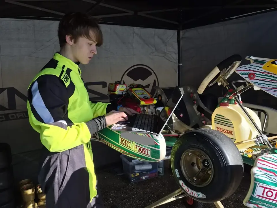 Jonah checking data on a laptop beside the kart between sessions